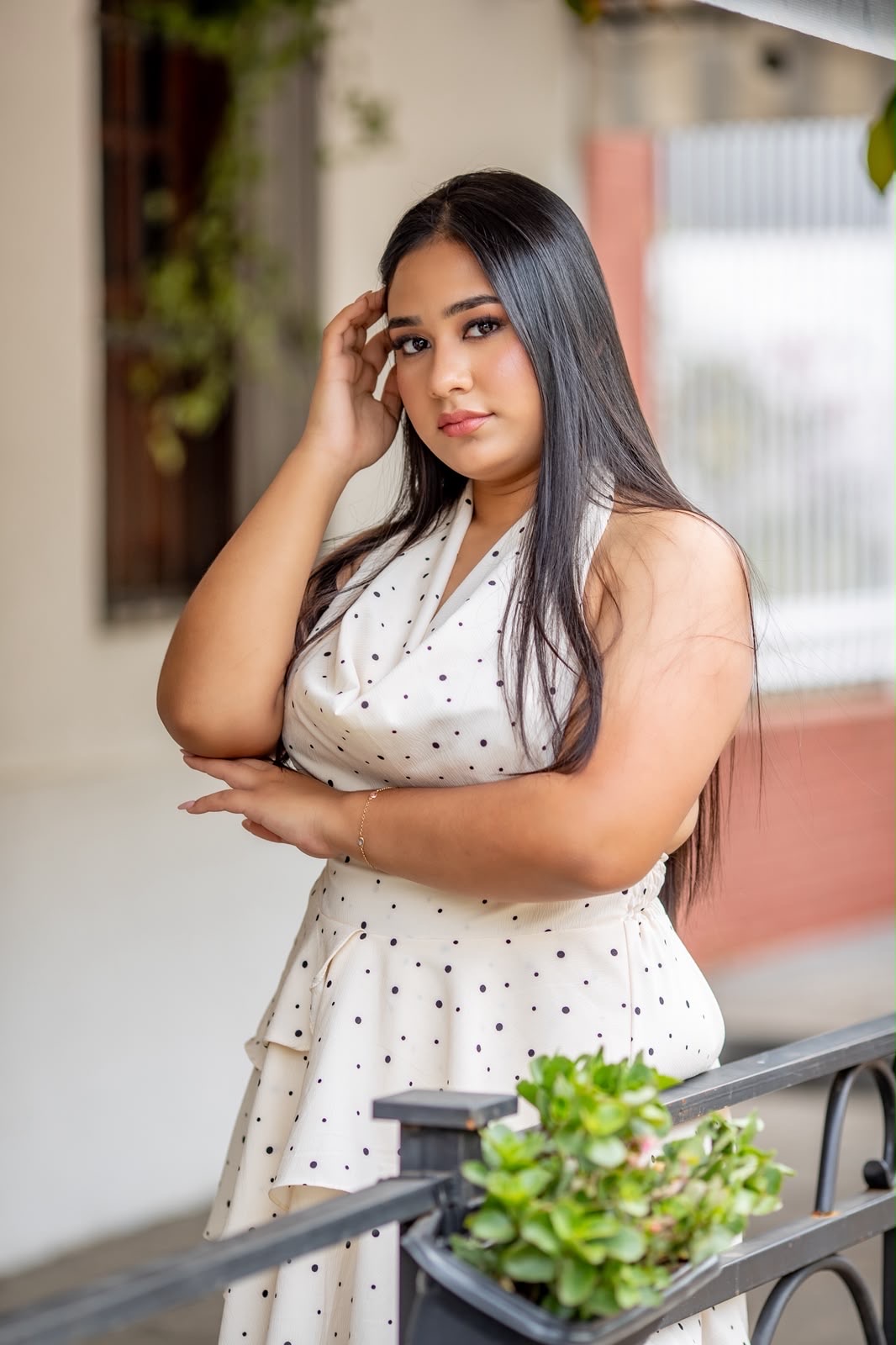 Airi con vestido blanco, apoyada en una baranda entre plantas